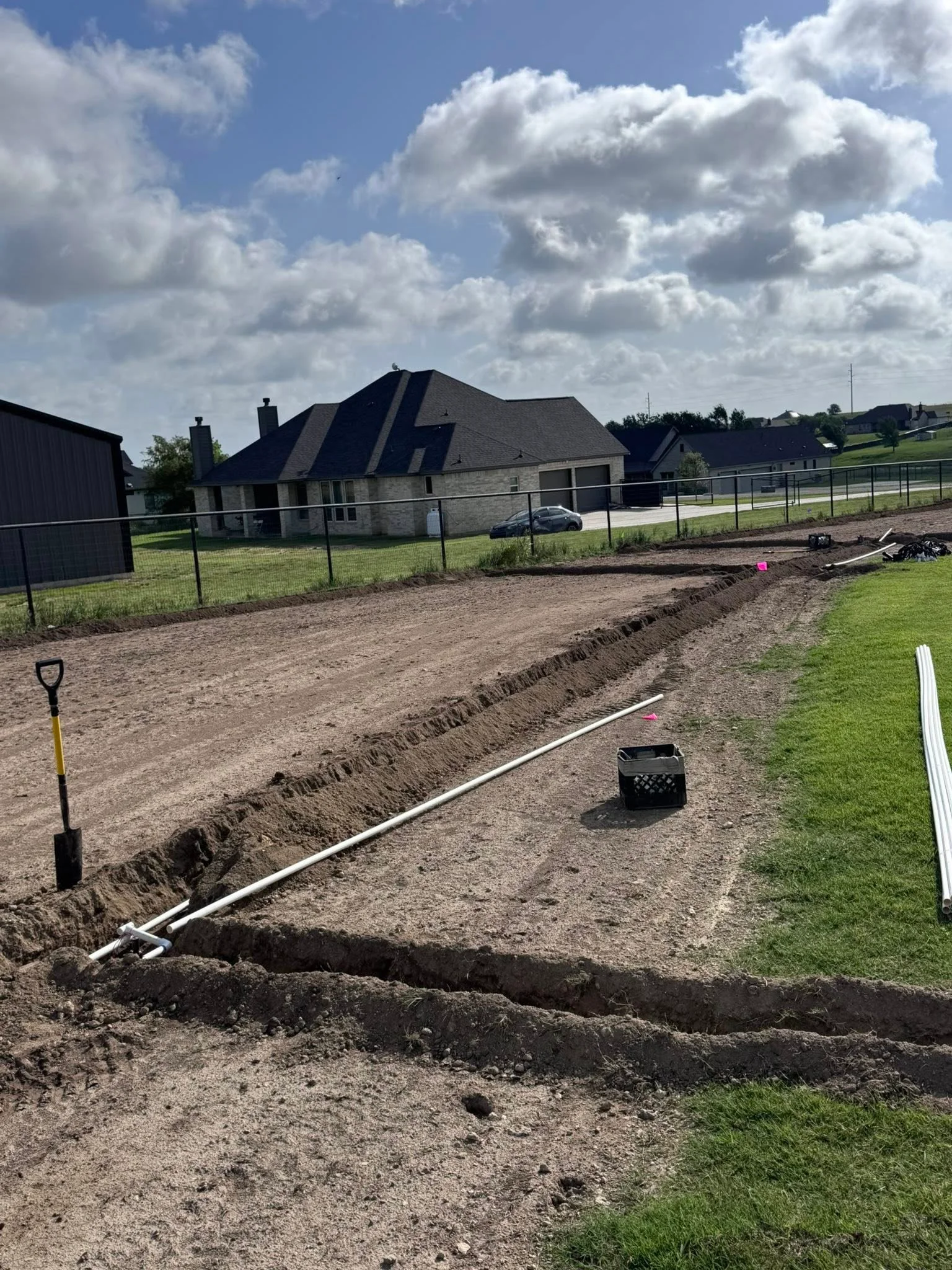 Residential driveway excavation with trenched drainage lines and PVC piping on rural property