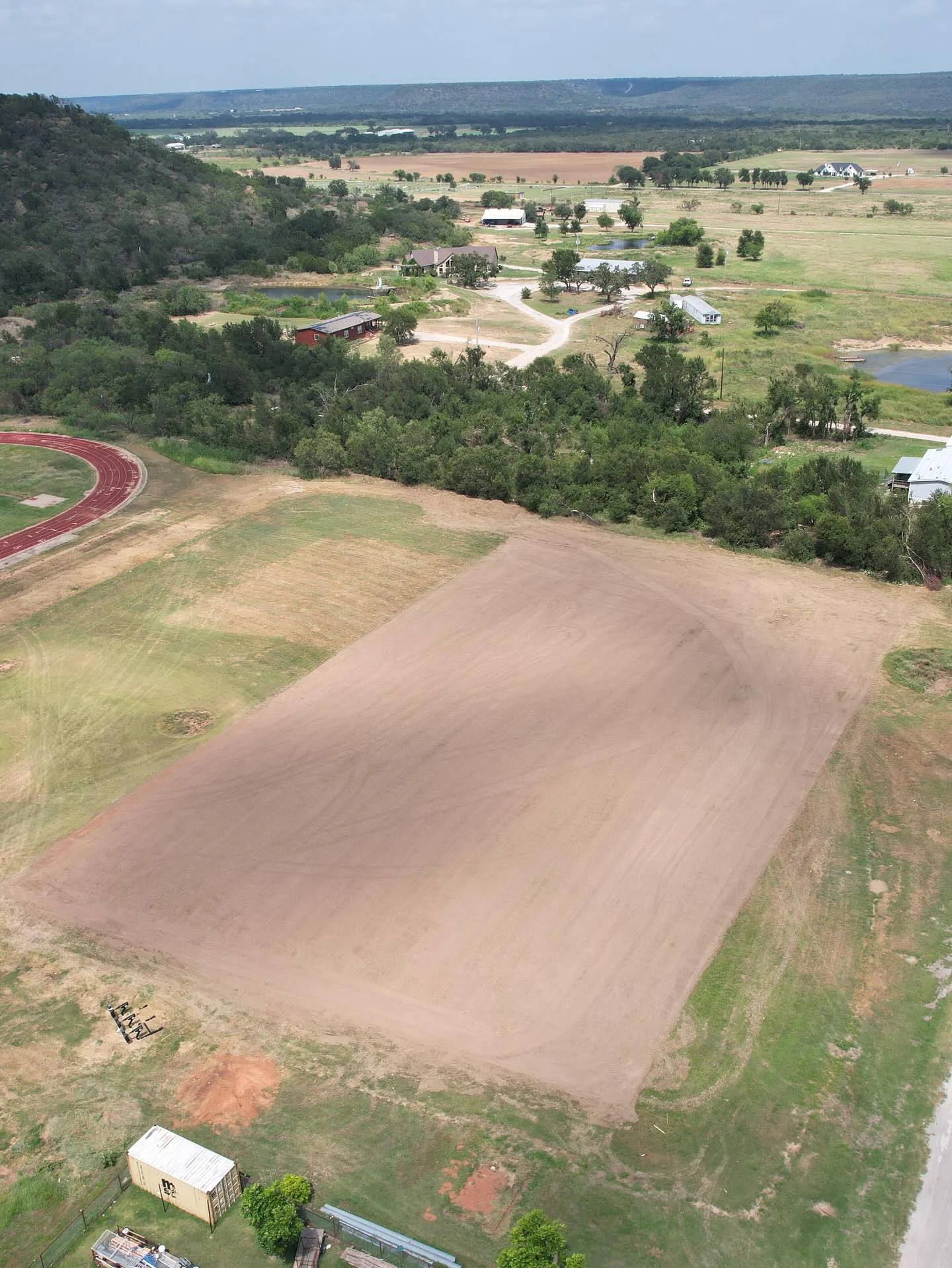 Aerial view of graded dirt pad on rural property with red clay soil in Weatherford, TX